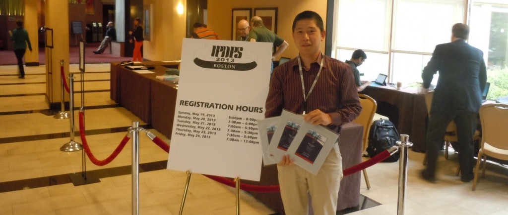 Wei Wang standing in front of symposium sign with awards